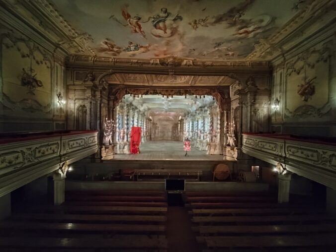 Barokové divadlo s pôvodnými kulisami, drevenými stĺpmi a kostýmom na javisku, zachované v plnej funkčnosti.