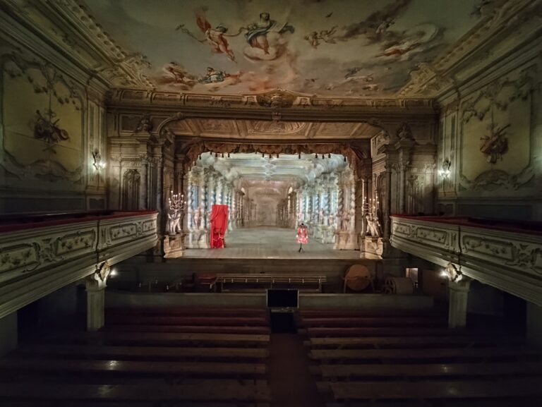 Barokové divadlo s pôvodnými kulisami, drevenými stĺpmi a kostýmom na javisku, zachované v plnej funkčnosti.