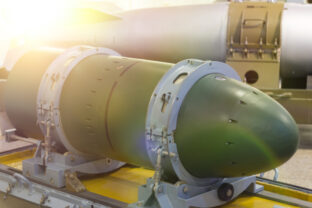 A warhead on a transport stand, against a rocket.