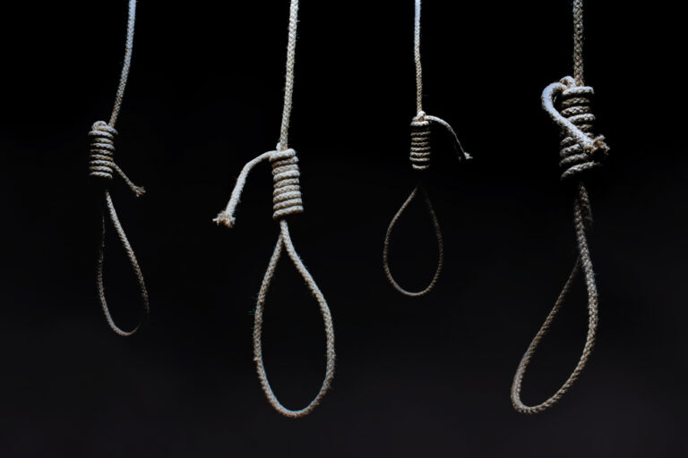 Dark scary hanging nooses on black background.