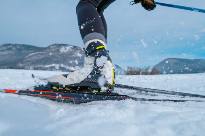 LOW ANGLE: Professional nordic skiing athlete pushes off her ski and poles.