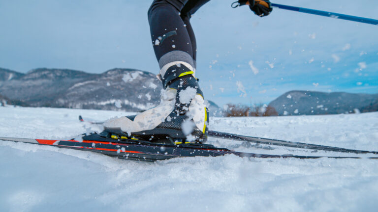 LOW ANGLE: Professional nordic skiing athlete pushes off her ski and poles.