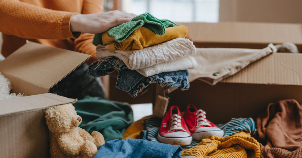 Woman sorting an old out of use kid toy, clothes and shoes in box for charity or upcycling