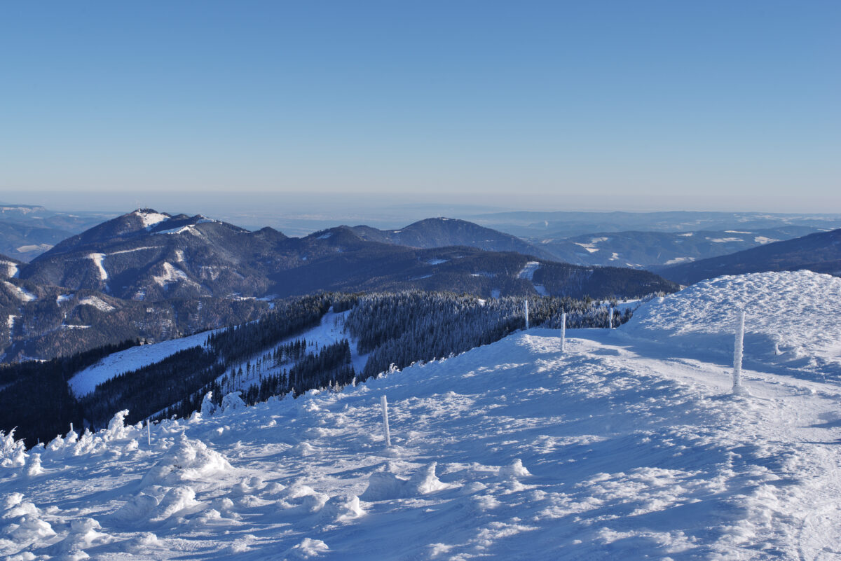 Blue sky above snow and frost covered winter landscape, long distance view. Stuhleck, Styria, Austria. In the background the mountain Sonnwendstein is visible.