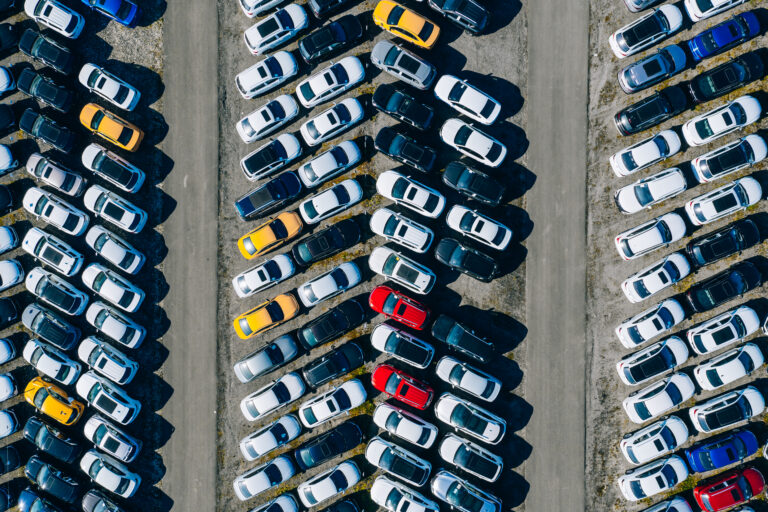 Aerial drone view of Parking lots. New hybrid or electric cars storage area. Many colorful cars parked in a rows
