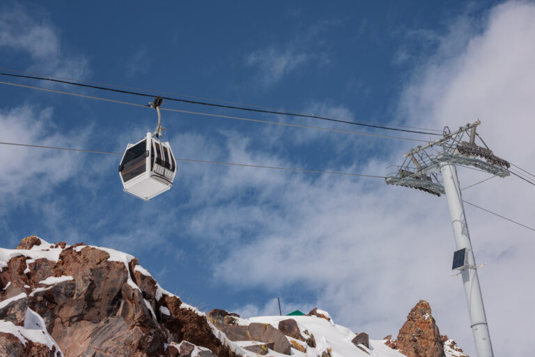 Snow covered mountains in Kabardino Balkaria with ski lifts. The landscape features rocky terrain and cloudy skies, creating a winter sports atmosphere.