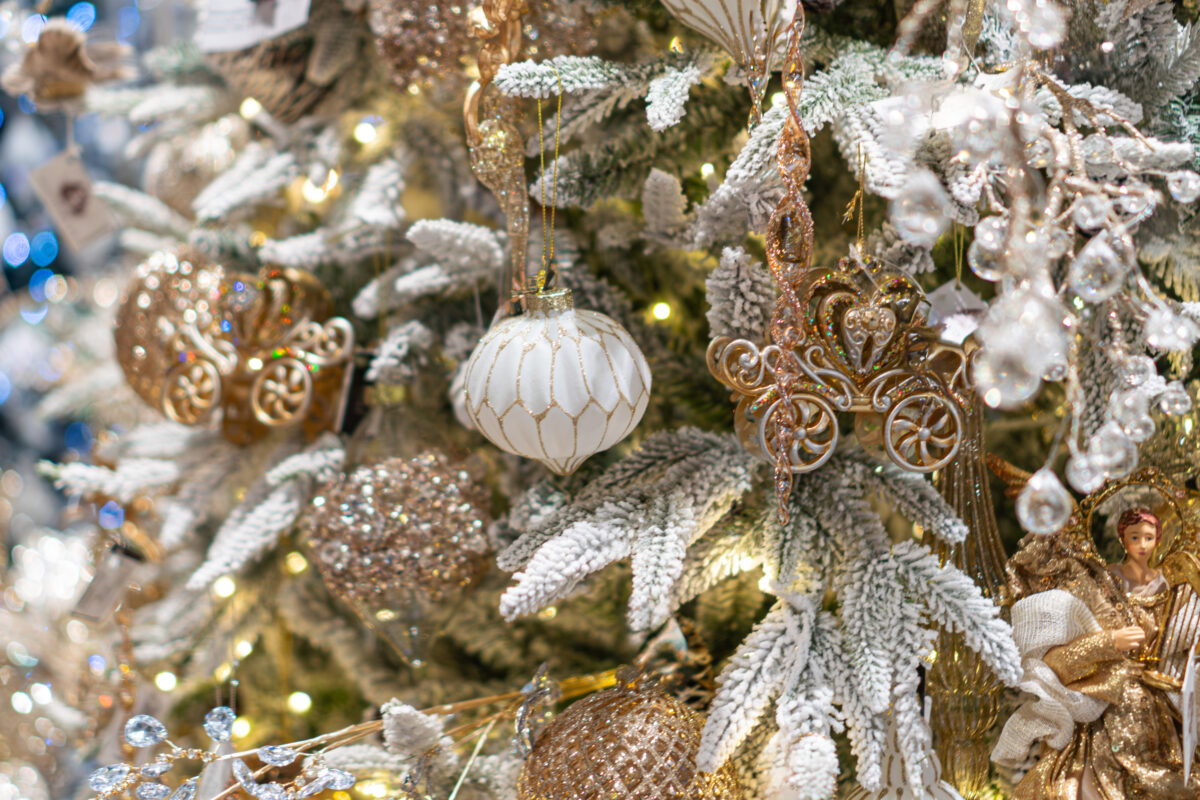 Festive Christmas tree with mixed ornaments, gold and silver metallic decorations, white and beige spherical ornaments, warm lighting, textured branches, magical winter scene