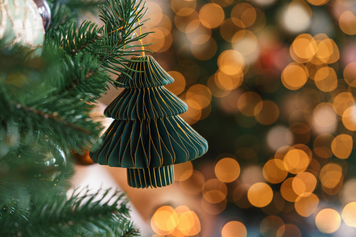 Dark green Christmas tree paper ornament with glowing golden bokeh holiday lights background