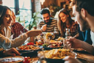 Joyful group of pals enjoying pasta at a home gathering - Happy individuals sharing a meal - Lifestyle idea with friends and acquaintances commemorating turkey day - Vibrant edit.