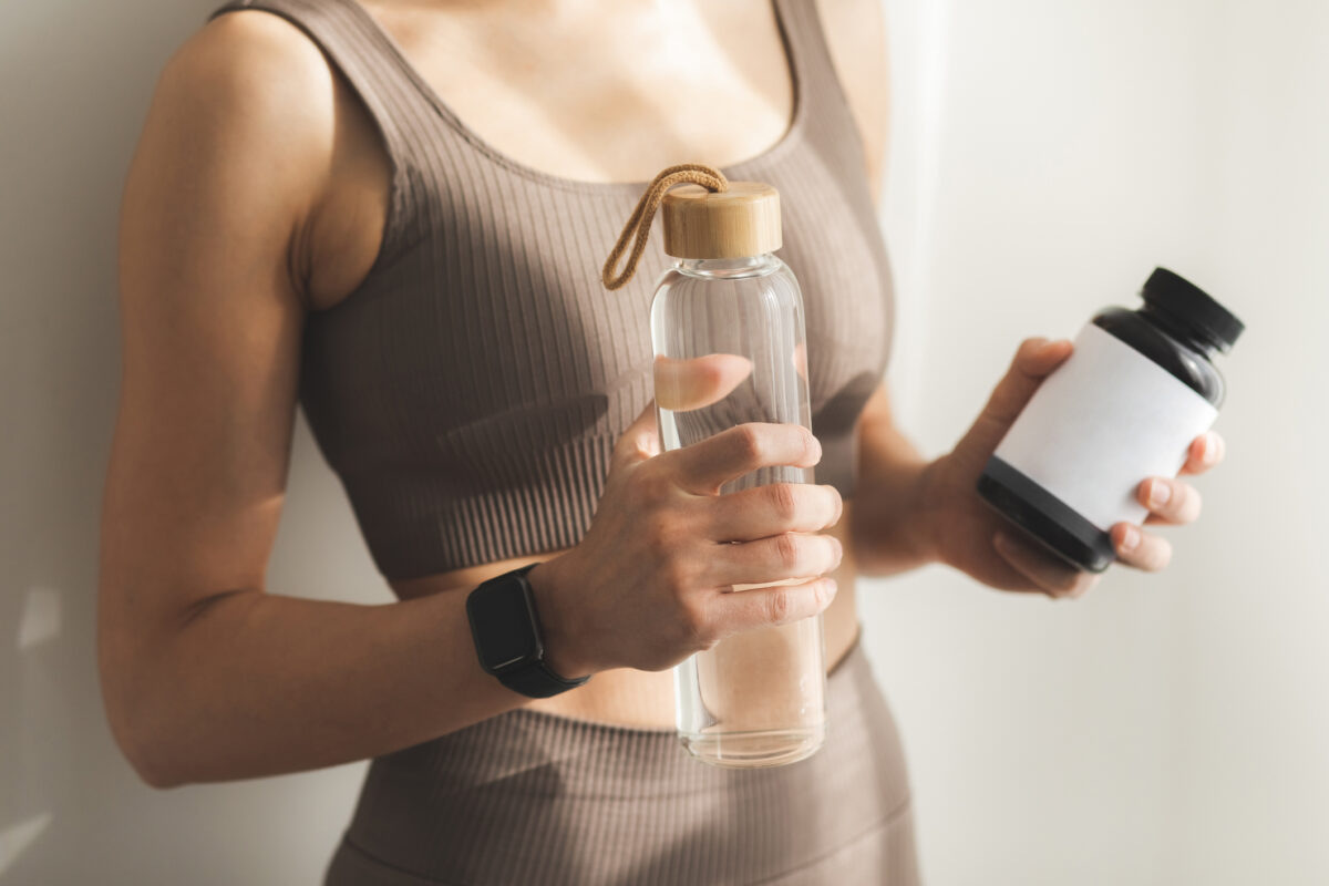 Woman holding bottle of dietary supplements or vitamins in her hands.