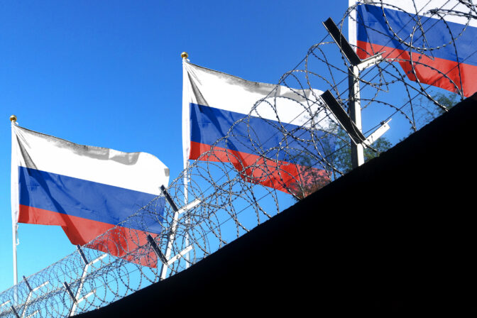 The Russian flag hangs in the cloudy sky outside the prison's barbed wire. waving in the sky