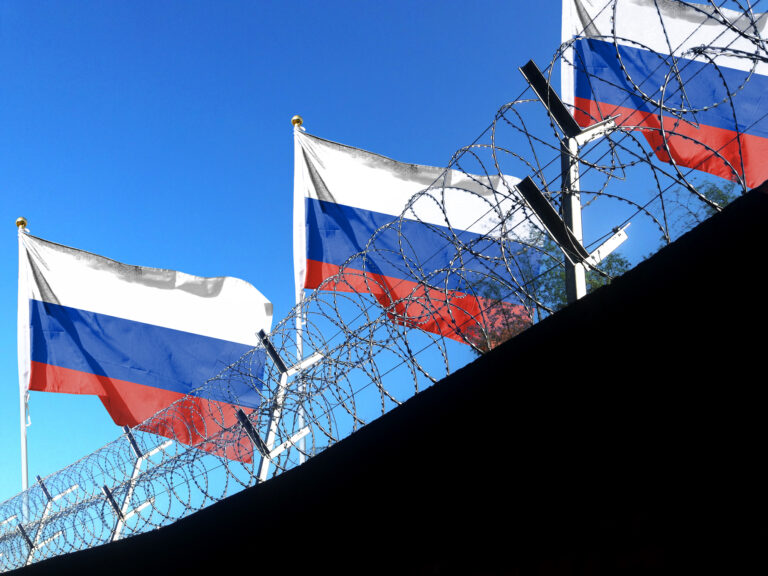 The Russian flag hangs in the cloudy sky outside the prison's barbed wire. waving in the sky