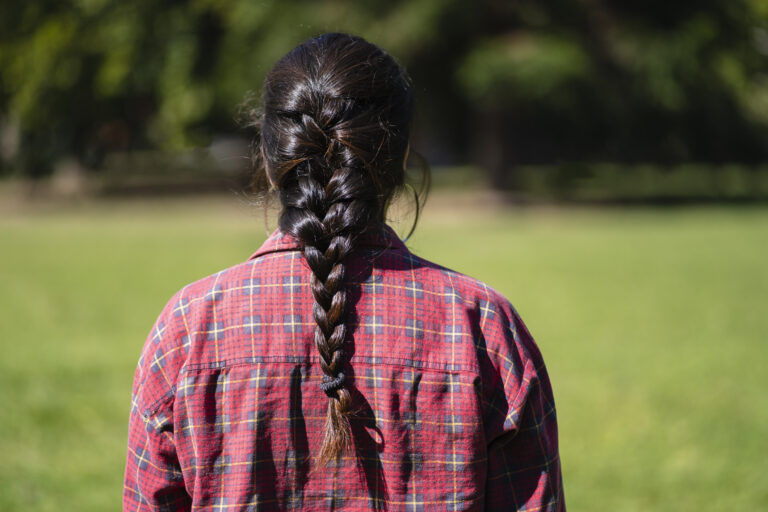 Latin woman from behind wearing a braid in a park
