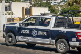 A municipal police truck from Los Cabos with the designation DST 1115 patrols a residential area.