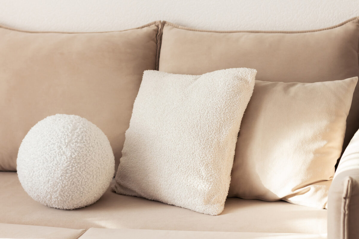 Stylish beige sofa with round and square boucle cushions white and beige colors.