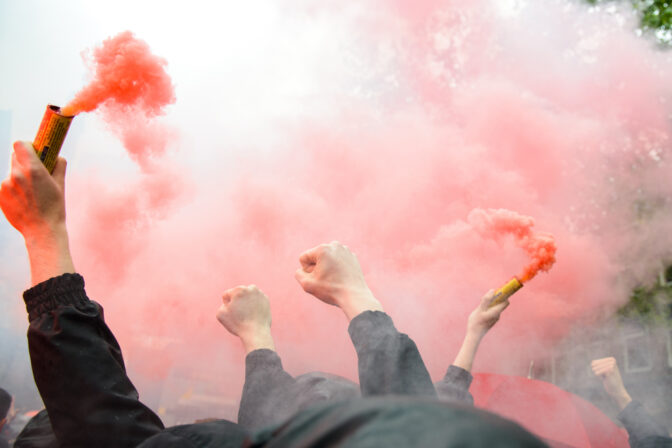 Cheering sports fans holding up bengal fireworks