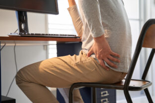 Japanese male businessman who suffers back pain from working from home