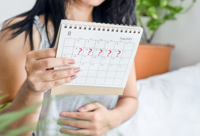 Woman hand holding calendar with question mark waiting for late blood period, amenorrhea concept
