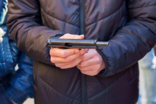A gun in the hands of a young man, selective focus. Reloading weapons. Shooting training. Background
