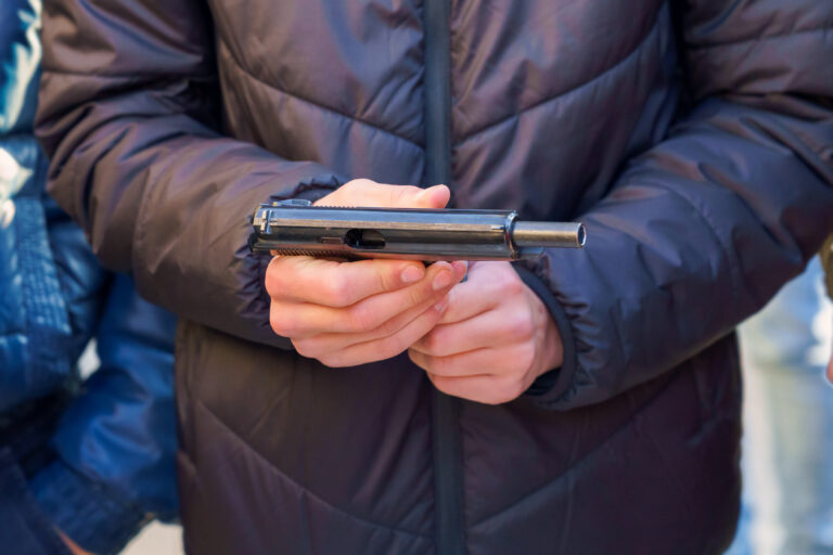 A gun in the hands of a young man, selective focus. Reloading weapons. Shooting training. Background