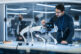 Portrait of Hispanic Engineer Using a Screwdriver While Building and Developing a Robot Dog Concept. Multiethnic Specialist Working in High Tech Research Laboratory with Modern Equipment.