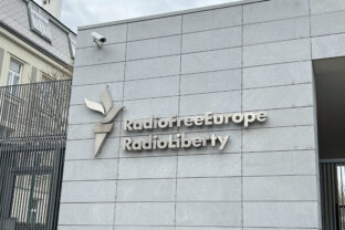 Sign "Radio Free Europe Radio Liberty" on gray building. RFE RL - international non profit broadcasting organization funded by the United States government. Headquarters in Prague - April 14, 2025.