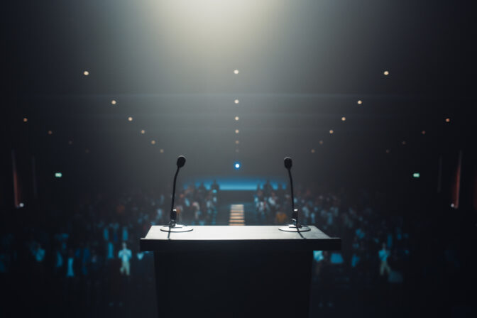 Modern Conference Stage With Two Microphones Under Spotlight, Ready for a Speaker to Come Up on Stage in a Dark Lit Auditorium. Public Speaking and Conference Presentation Concept