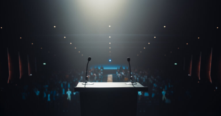 Modern Conference Stage With Two Microphones Under Spotlight, Ready for a Speaker to Come Up on Stage in a Dark Lit Auditorium. Public Speaking and Conference Presentation Concept
