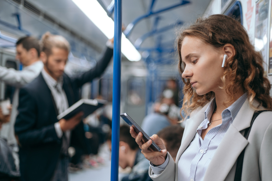 Young woman reads a text message on a subway train.