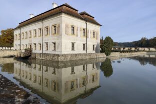 Panoramatický pohľad na Zámok Kratochvíle v Netoliciach s odrazom vo vodnej priekope, renesančný zámok inšpirovaný Benátkami