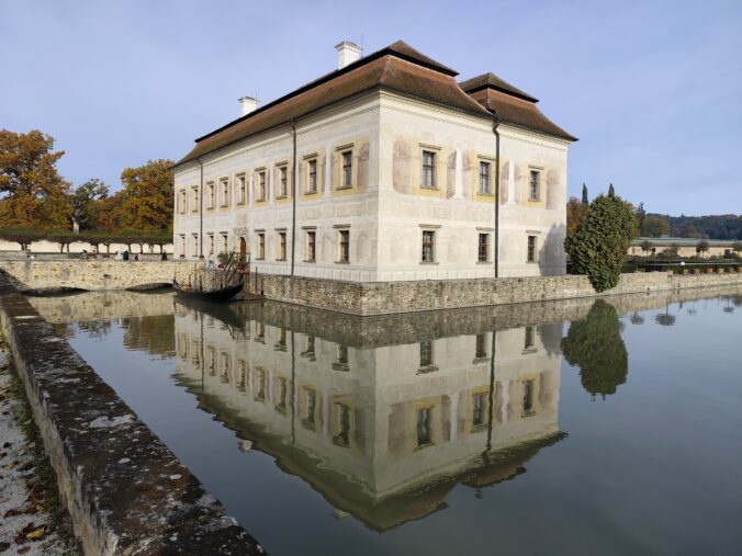 Panoramatický pohľad na Zámok Kratochvíle v Netoliciach s odrazom v vodnej priekope, renesančný zámok inšpirovaný Benátkami
