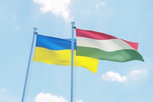 Hungary and Ukraine, two flags waving against blue sky