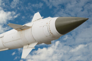 A missile with a warhead against the sky and clouds.