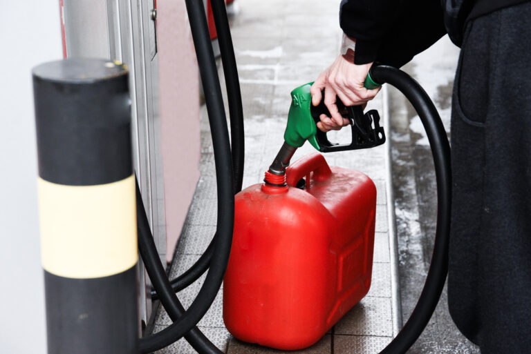 A man pouring fuel into a canister at a gas station.