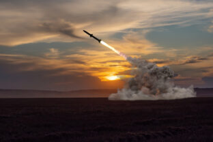 Rocket launch against the background of the evening field, the setting sun.