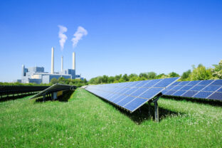 Energy production in a conventional dirty power plant compared to modern ecological alternative from renewable energy through solar electricity with solar panels in a green park - Munich, Germany