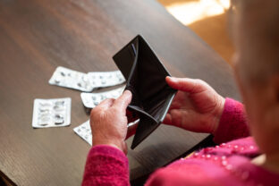 Elderly woman looking into empty wallet