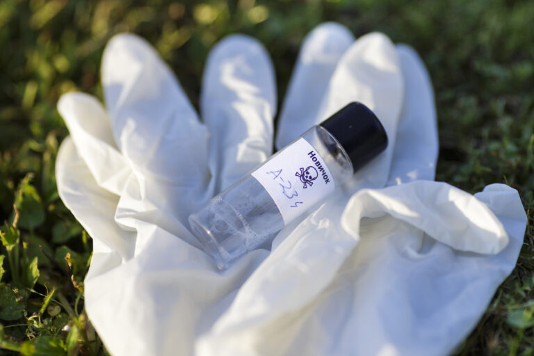 Illustration with mock up of Novichok agent (A 234) bottle and white rubber gloves on grass. Fictitious title on bottle in Russian: Novichok