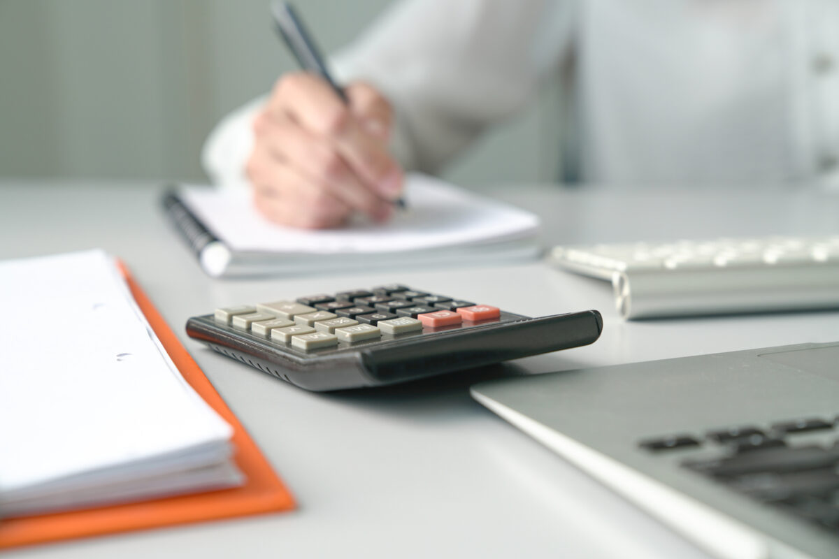 Office table view with Accountant at the background and focus on the calculator