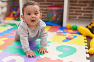 Adorable hispanic baby crawling on floor at kindergarten