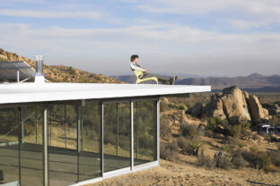 Man relaxing atop roof of prefabricated home