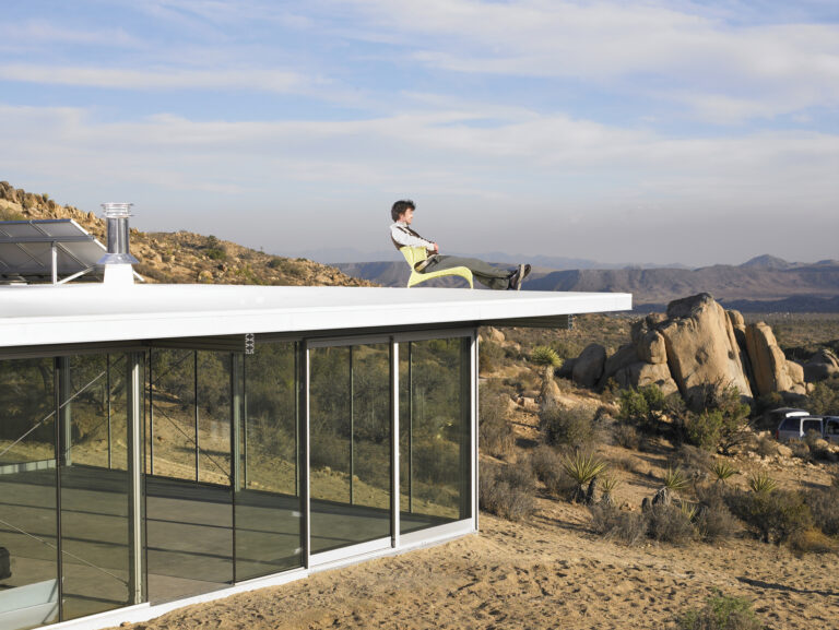 Man relaxing atop roof of prefabricated home