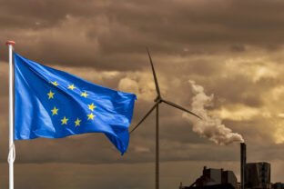 European flag in front of a polluting factory and wind turbine