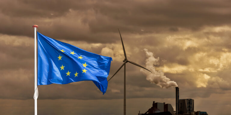 European flag in front of a polluting factory and wind turbine