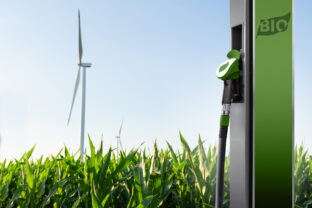 Biofuel refueling nozzle on a background of corn field with wind turbines