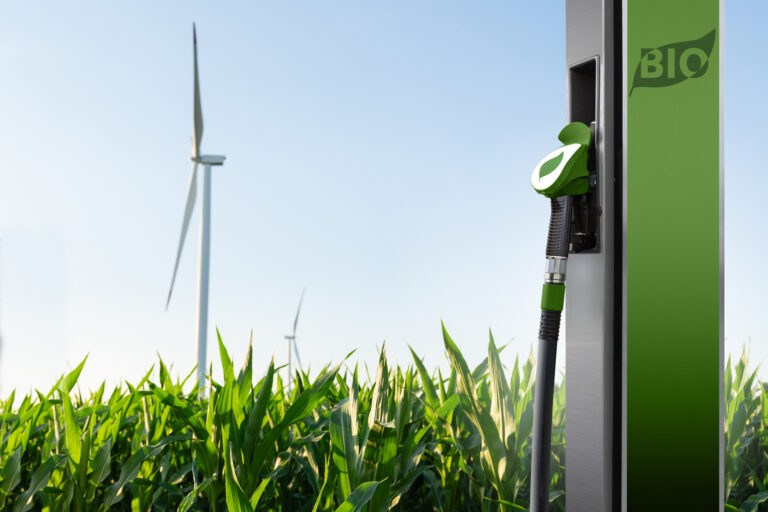 Biofuel refueling nozzle on a background of corn field with wind turbines