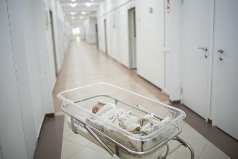 Newborn baby sleeps in a transparent plastic cradle, incubator in the maternity hospital. The baby is 2 days old.
