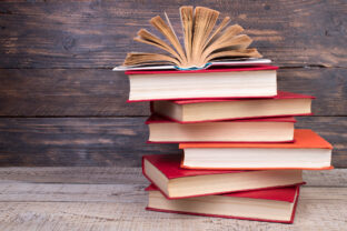 Composition with hardback books, fanned pages on wooden deck table and background. Books stacking. Back to school. Copy Space. Education background.