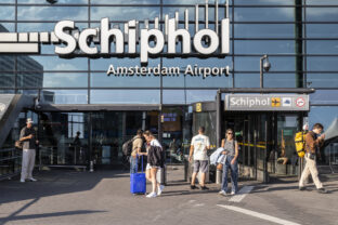 Travelers in front of the entrance to the central hall of Schiphol airport Amsterdam.
