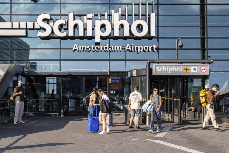 Travelers in front of the entrance to the central hall of Schiphol airport Amsterdam.